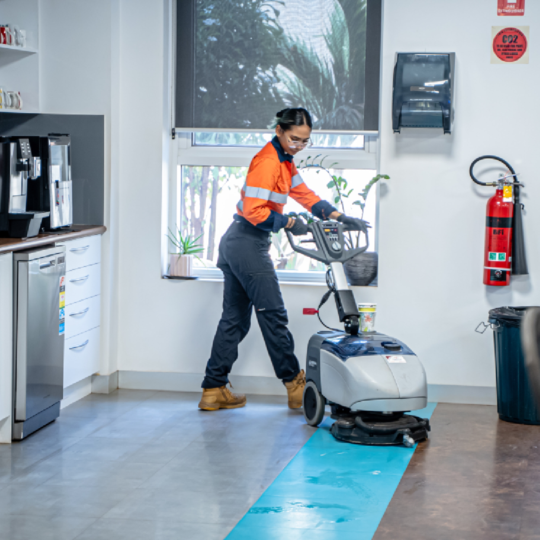 Kestrel Cleaning Services team member using a commercial floor scrubber in an office kitchen
