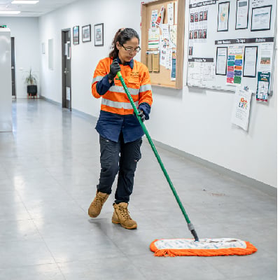 Female cleaner in high-vis uniform mopping a polished hallway