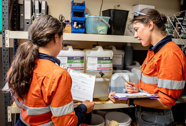 Two Kestrel Cleaning team members in high-vis uniforms checking paperwork in front of commercial cleaning products